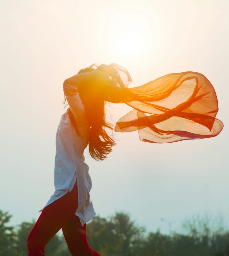 Frau mit wehenden Haaren und einem roten Tuch, umgeben von sanftem Licht. Frau mit wehenden Haaren und einem roten Tuch, umgeben von sanftem Licht.